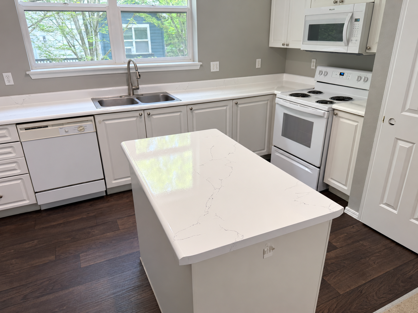 White marble-look kitchen countertops and island with fine gray veining
